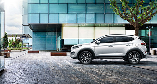 Side view of silver Tucson parked in font of the building