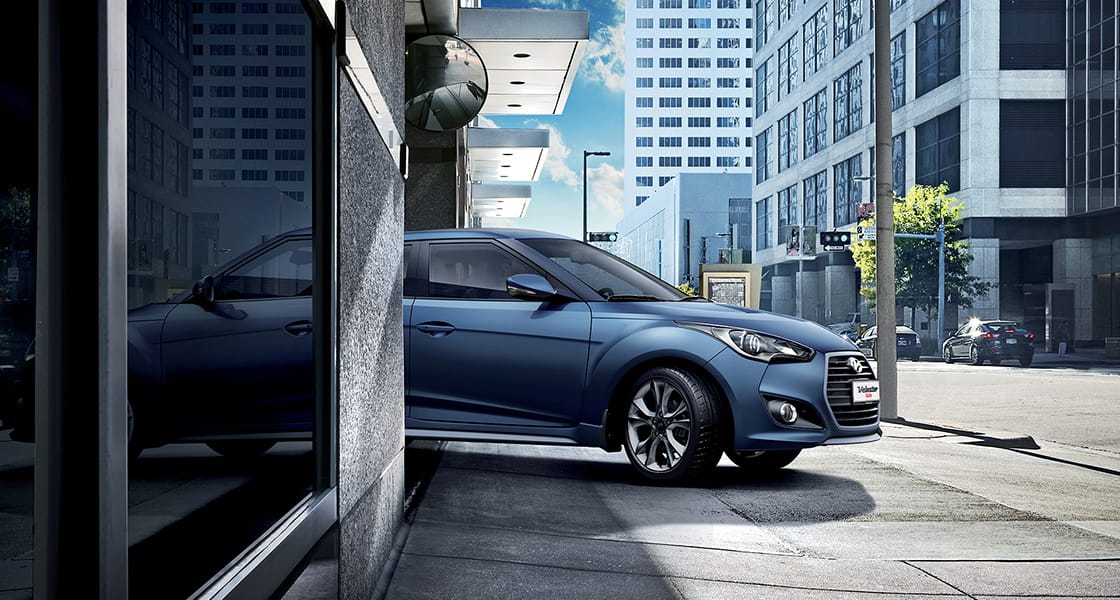 Side view of navy Veloster Turbo driving out from the basement parking lot