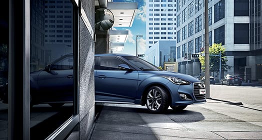 Side view of navy Veloster Turbo driving out from the basement parking lot