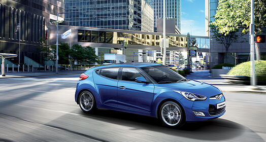 Right side front view of blue Veloster driving on the road in the city
