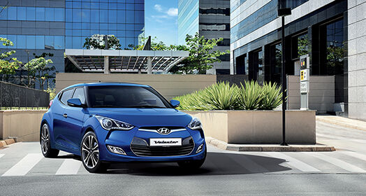 Side front view of blue veloster driving out from the basement parking lot