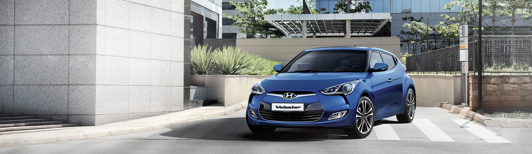 Blue color Veloster is placed in front of a modern building