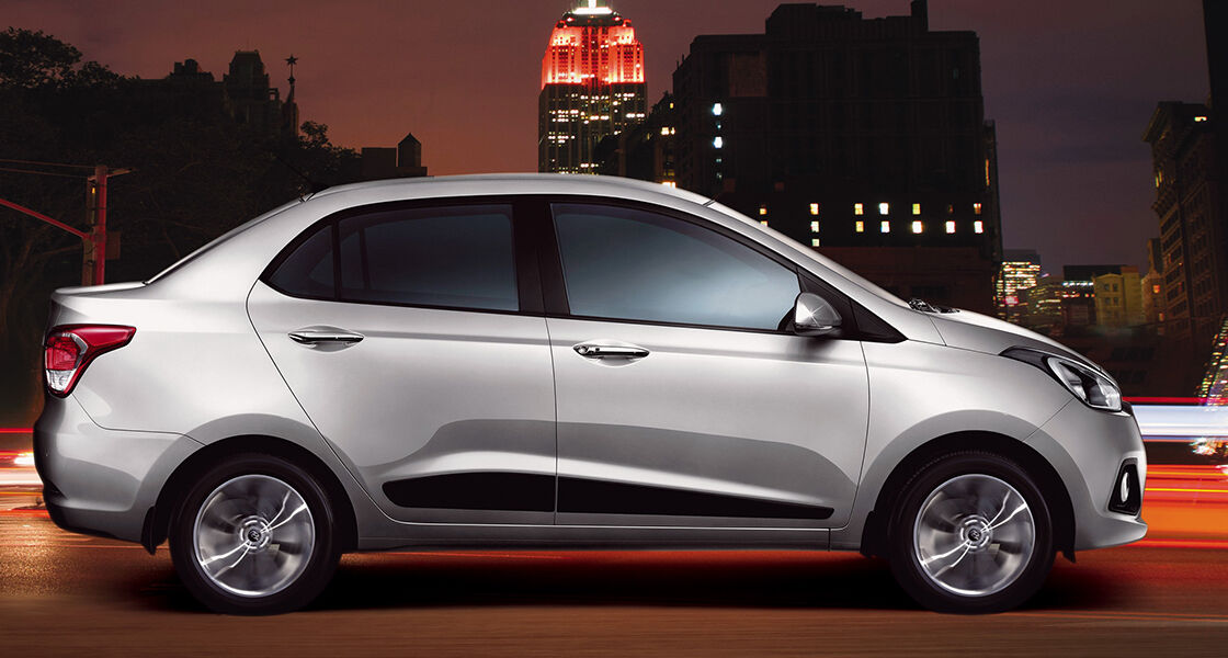 Side view of silver Xcent driving on the road at night