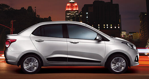 Side view of silver Xcent driving on the road at night