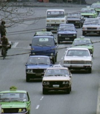 Cars, including the original Hyundai Pony, driving down the highway.