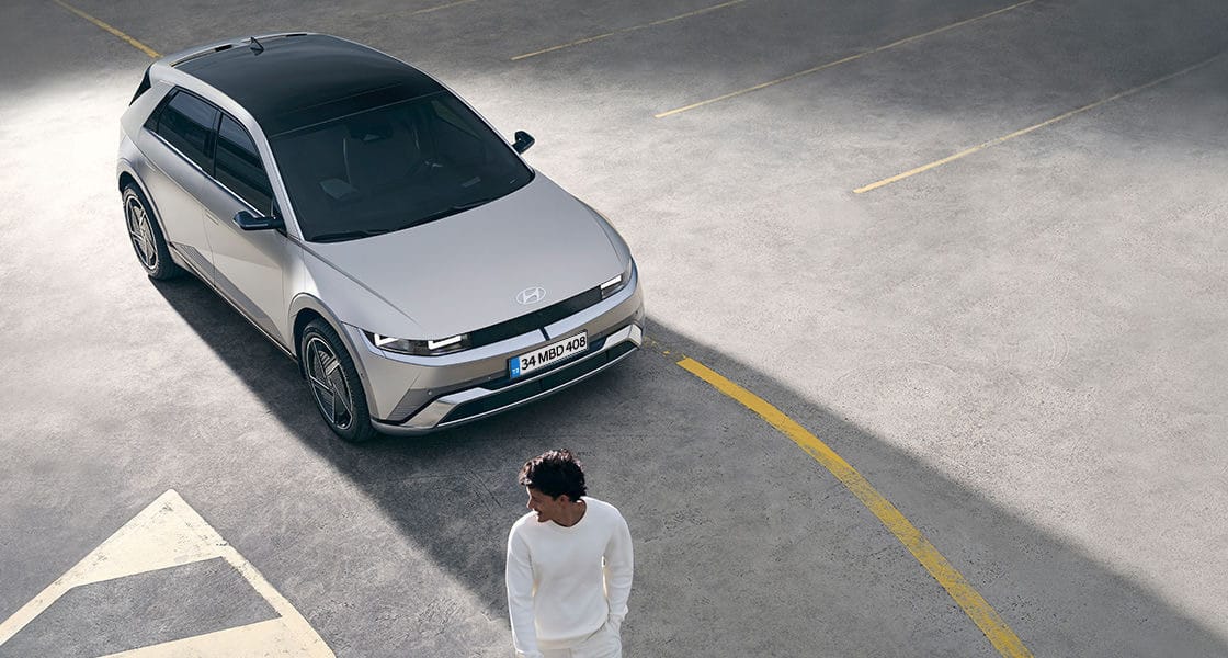 Aracın önünde yürüyen bir adam.