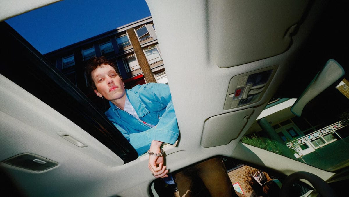 Yeni Hyundai INSTER küçük elektrikli otomobilinin cam tavanından bakan bir adam.