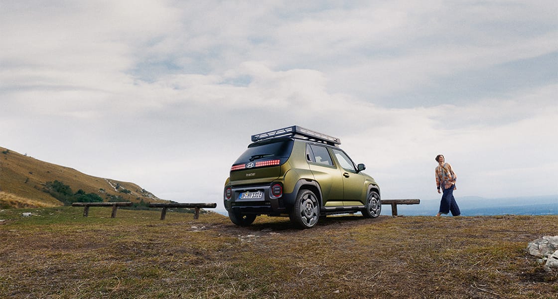 Tepeye park etmiş halde Hyundai INSTER Cross'un arka çapraz görünümü.