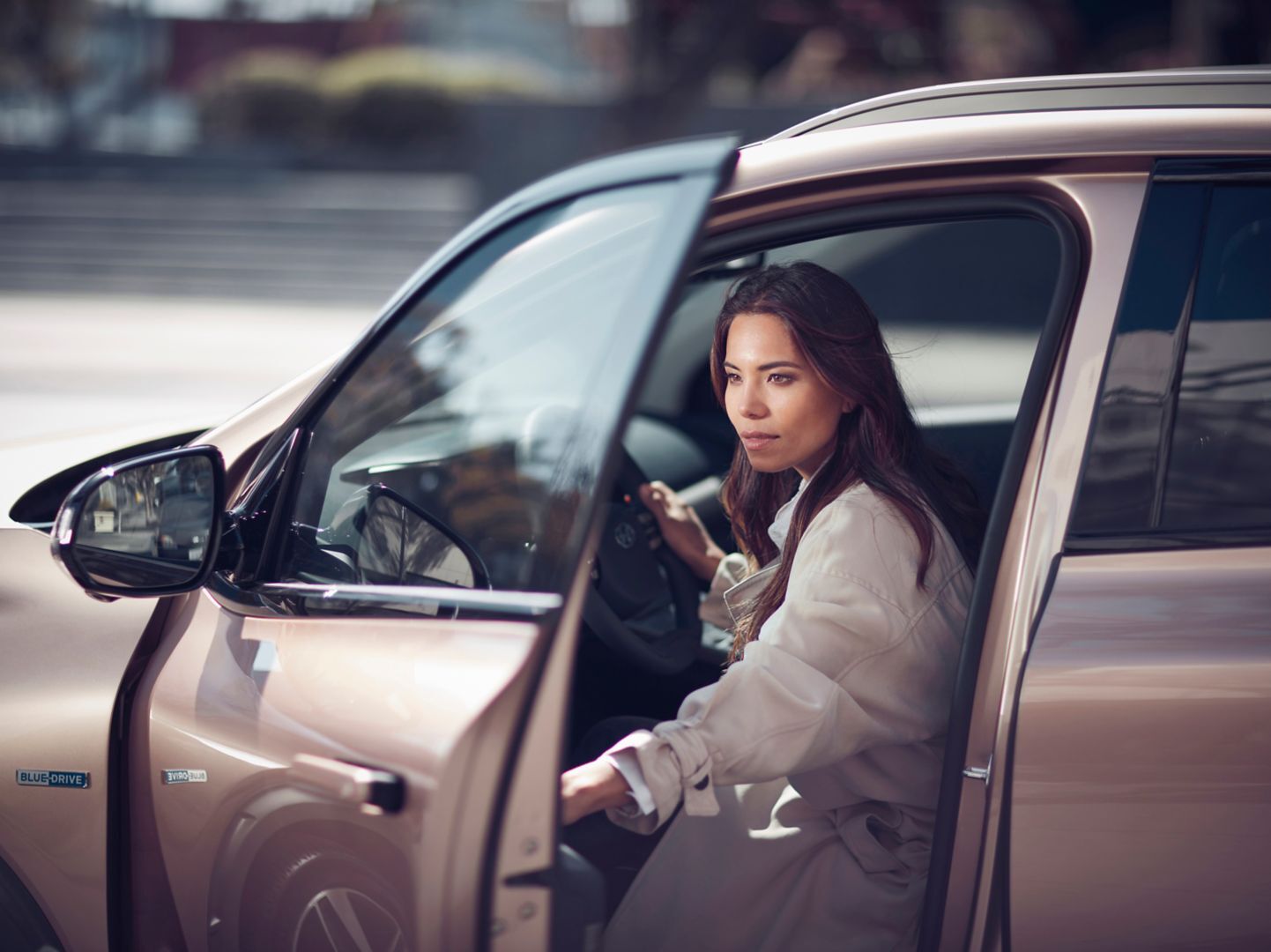 A woman getting into the driver's seat of a Hyundai NEXO hydrogen fuel cell vehicle.