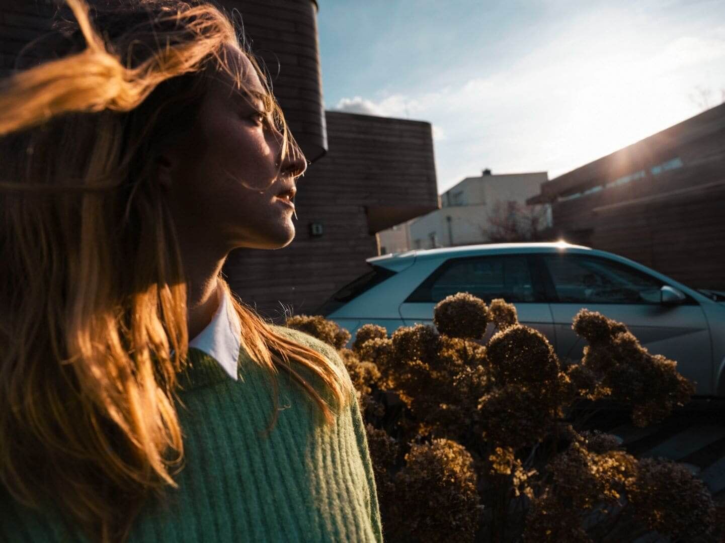 A woman in the sunshine standing next to the Hyundai IONIQ 5 electric CUV.