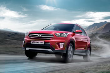 Avtoturargohda jigarrang i20 modeli va rasmning oʻng tomonida oq rangli bino tasviri tushirilgan