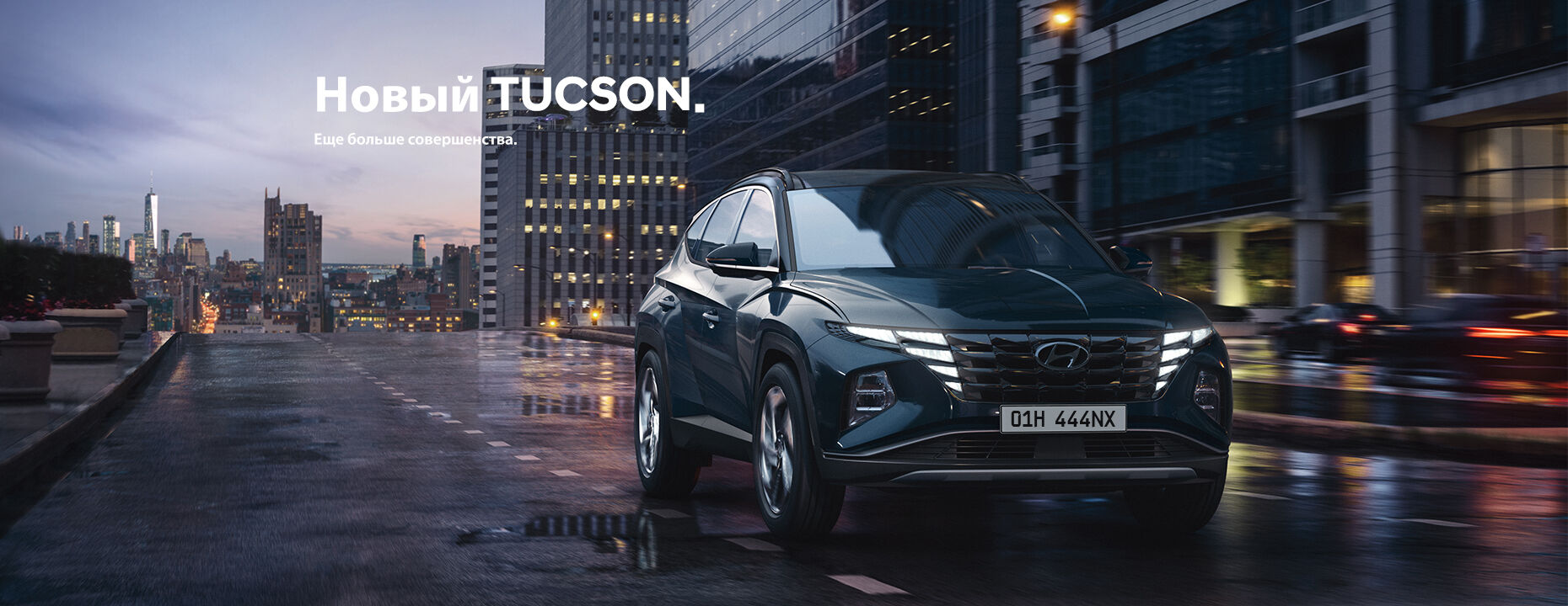 Синий Hyundai Tucson едет по дороге на фоне городских зданий