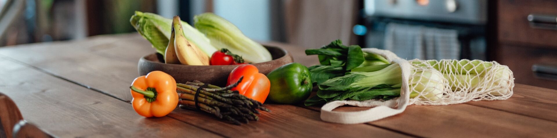 An assortment of brightly colored vegetables sprawled out on a wooden table.