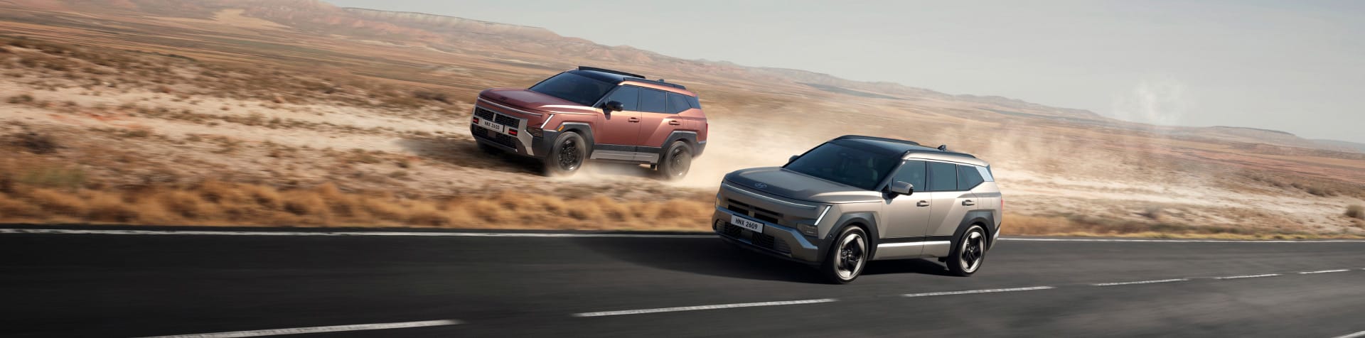 Two all-new Hyundai TUCSON models driving side by side, one on an open road and the other across dusty off-road terrain.