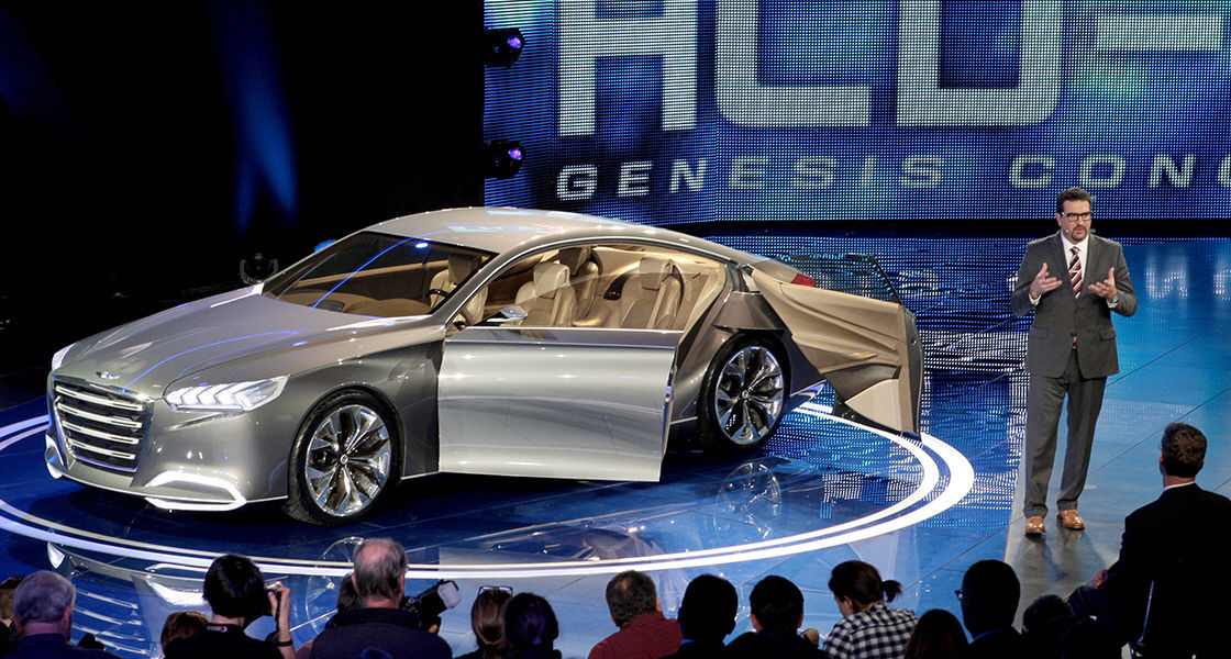 A presenter standing next to HCD-14 Genesis on the stage in front of the crowd