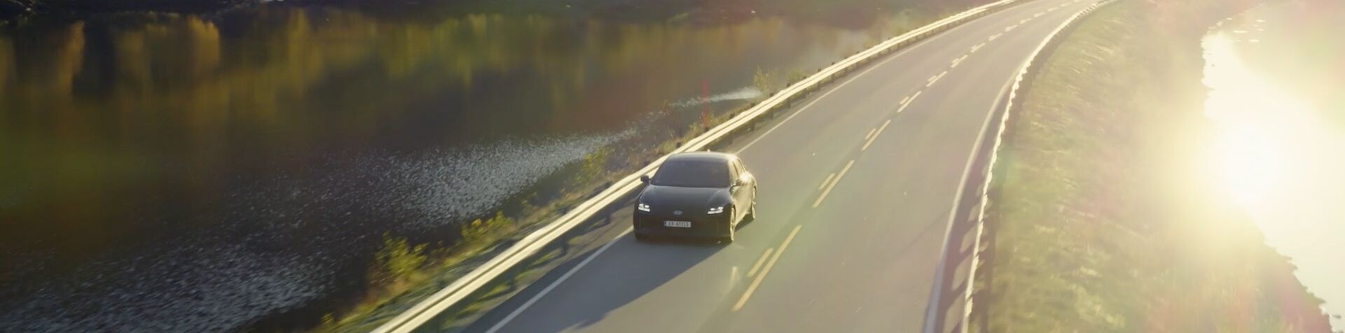 An IONIQ 5 drives next to a lake.