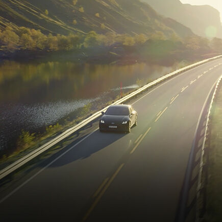 An IONIQ 5 drives next to a lake.