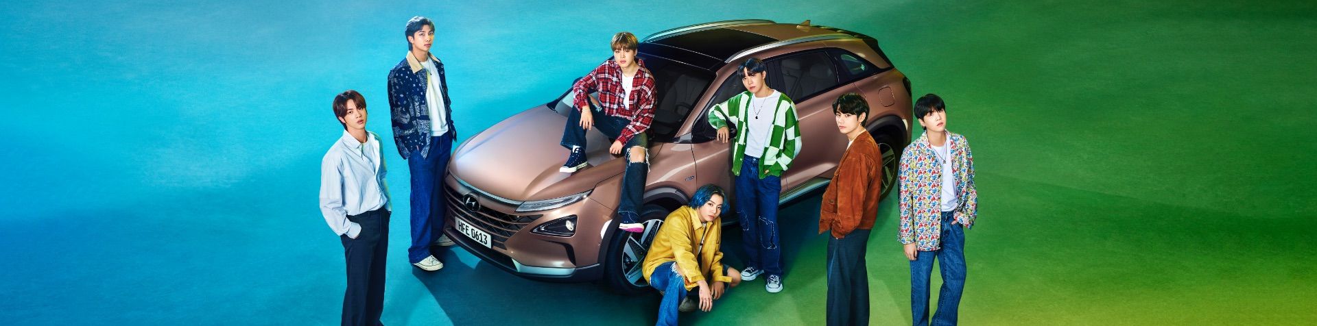 한국 보이그룹 BTS 7명 멤버가 파란색, 초록색 배경으로 현대 넥쏘 자동차 주위에 서 있다.