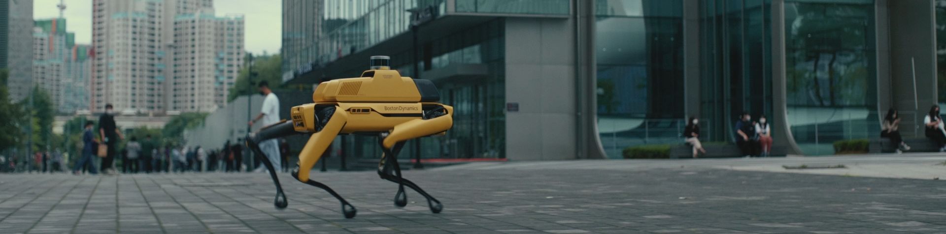 서울 도심을 걷고 있는 스팟의 모습입니다. 다리가 4개인 밝은 노란색 로봇 스팟의 측면에는 ‘보스턴 다이내믹스(Boston Dynamics)’가 쓰여 있습니다.