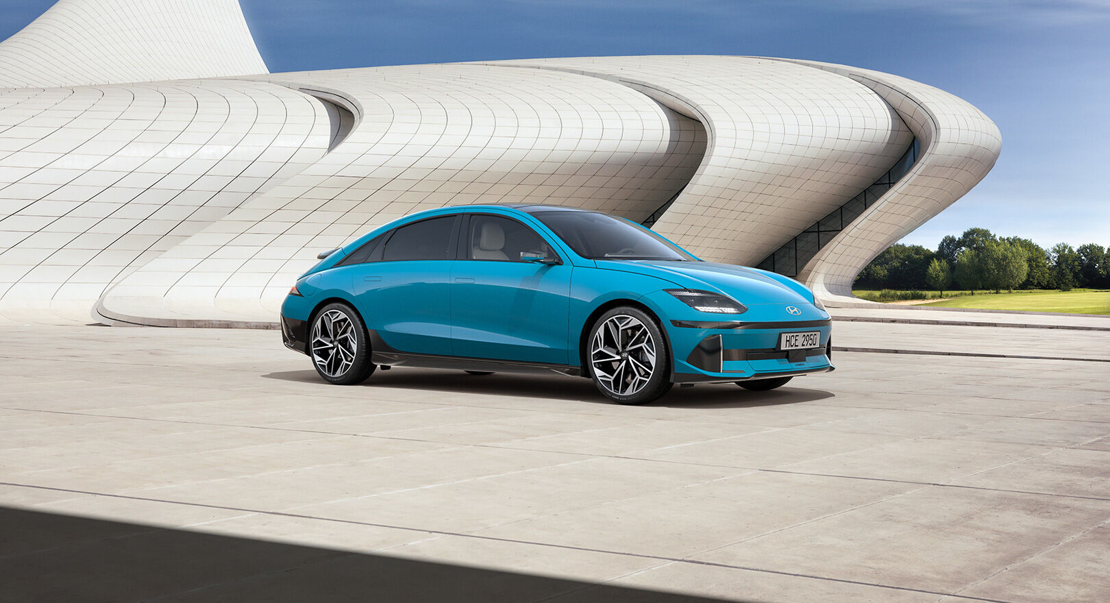 a blue car next to a white unique structure