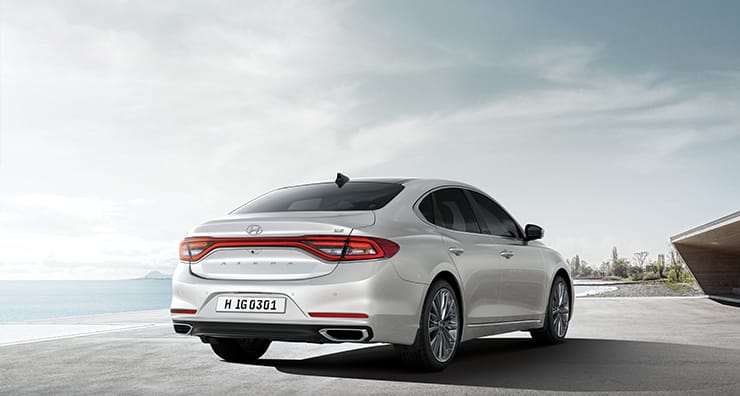 Right side rear view of white cream Azera parked beach.