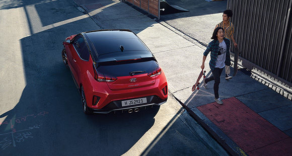 A woman and left side rear view of red veloster parking on the road 