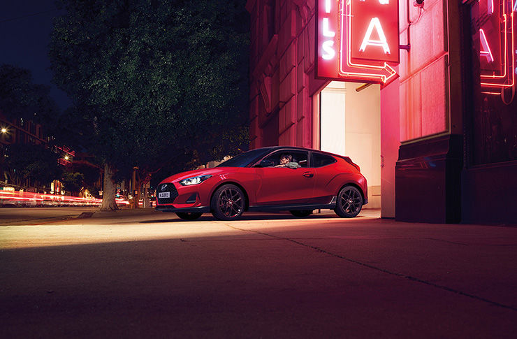 Right side view of red Veloster that opened trunk parked on the road.