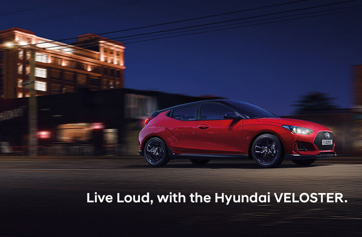 Right side view of the red VELOSTER driving on the road.