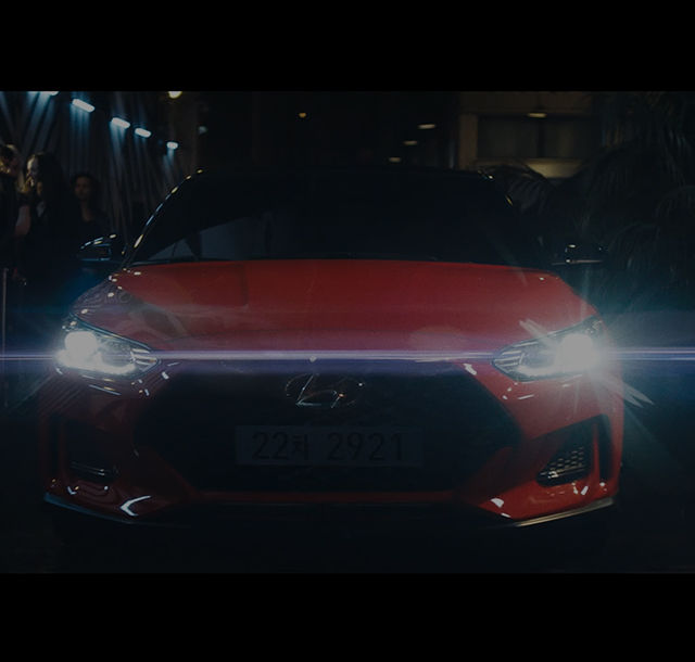 Front view of the red Veloster turn on its headlights.