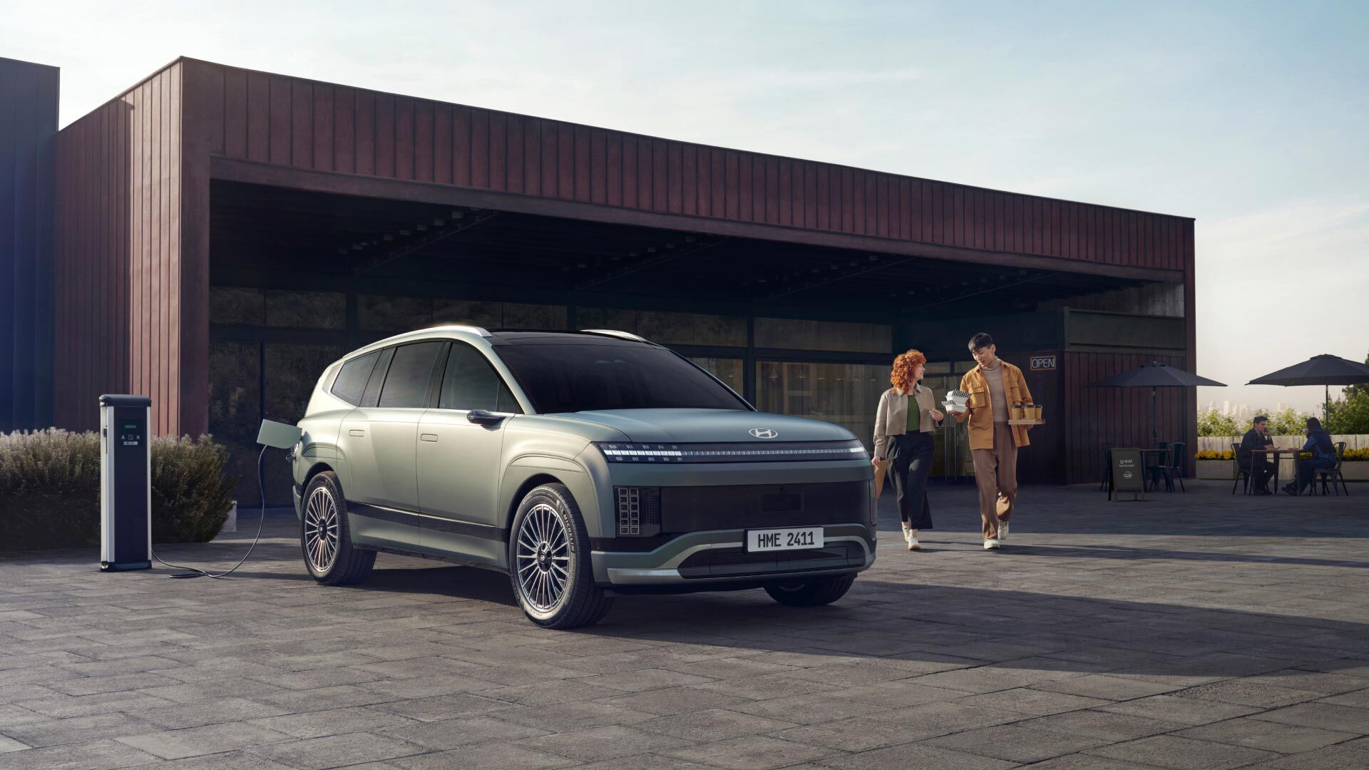 Two people with snacks heading towards a charged Hyundai IONIQ 9.