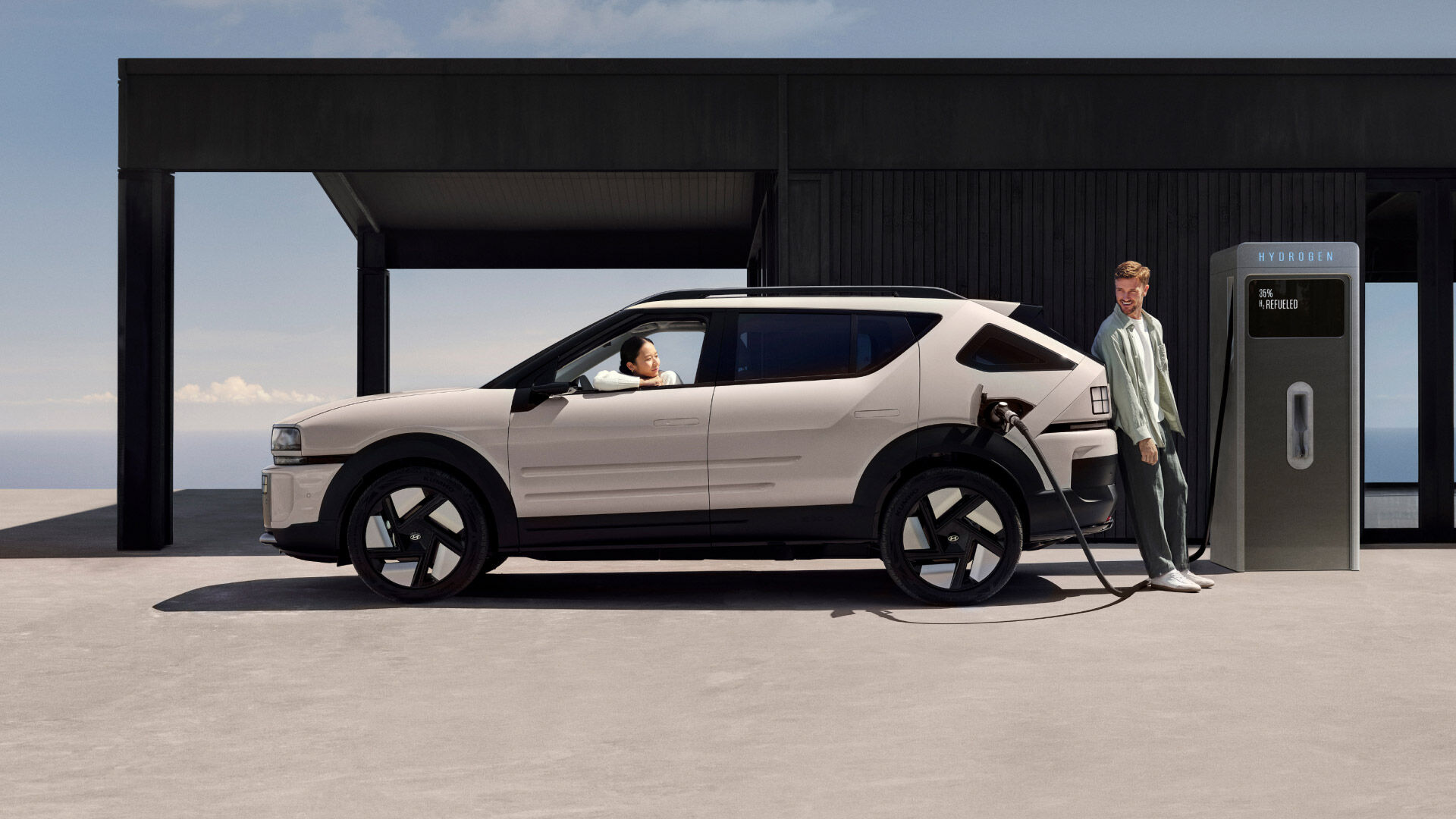 A woman in the driver’s seat, looking at a man charging the all-new NEXO