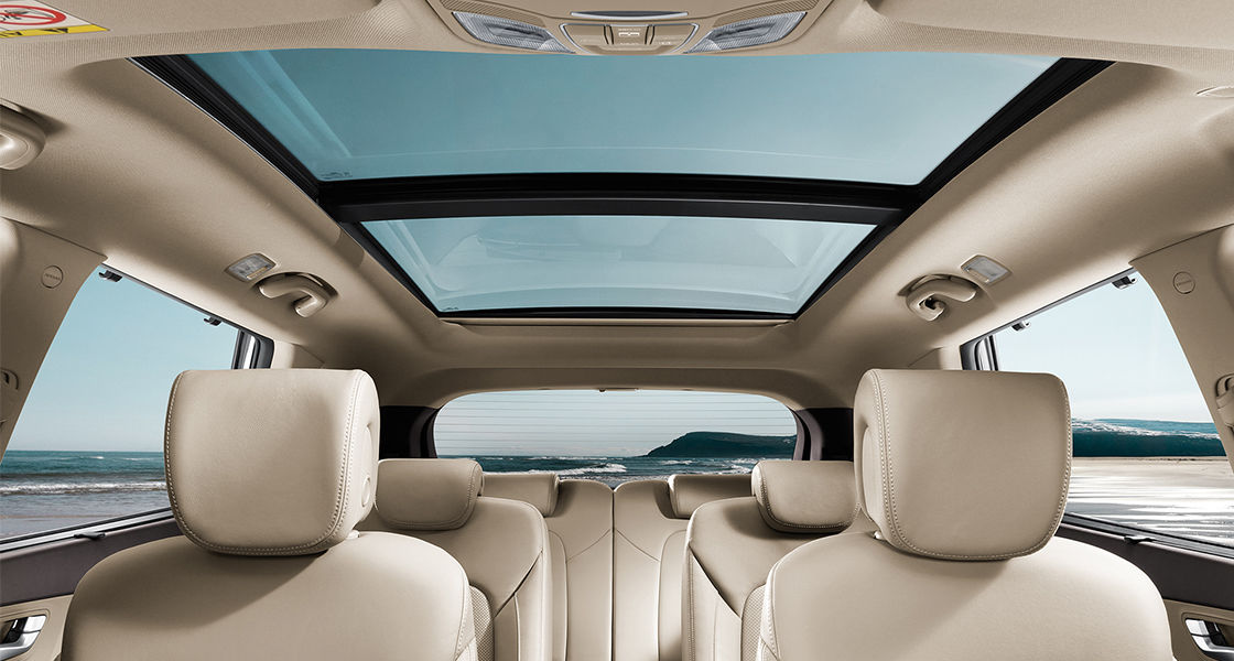 Panoramic view of beige interior with sunroof opened on a clear day