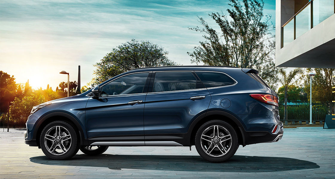 Side view of navy Grand Santafe with sunset