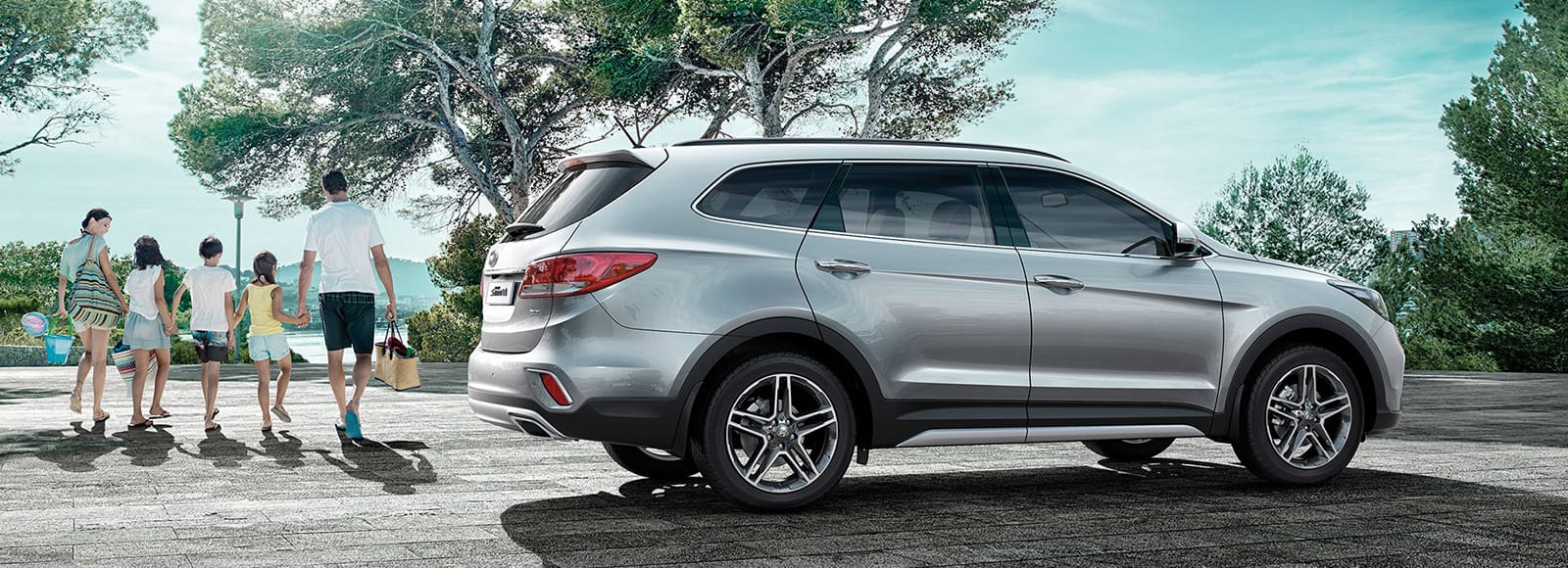 Side view of silver Grand Santa Fe parked outdoor and people passing behind