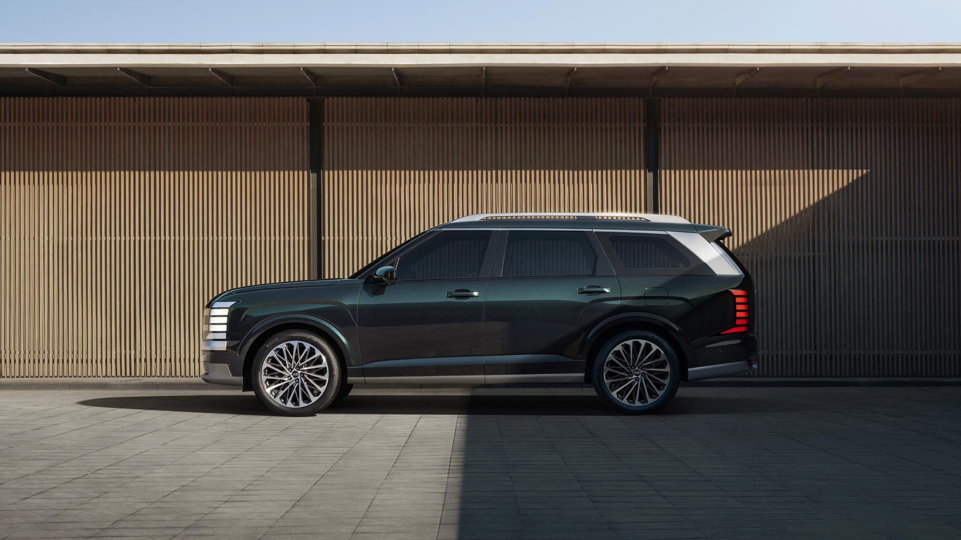 The all-new PALISADE side view, in front of a wall