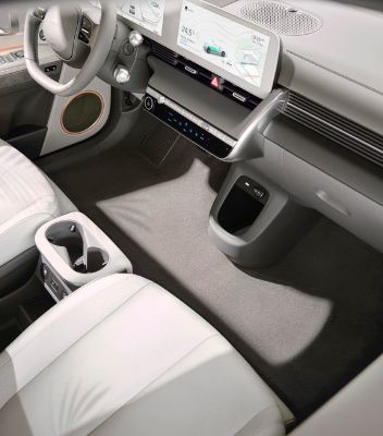 A close-up of the front seats and console of the IONIQ 5. The seats, lining and carpet are covered sustainable fabrics in cream and gray tones.