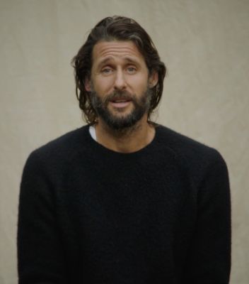 Portrait photo of David de Rothschild. He has long dark hair and a beard and is wearing a black pullover. 