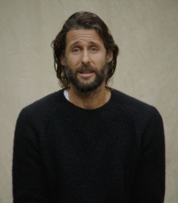 Portrait photo of David de Rothschild. He has long dark hair and a beard and is wearing a black pullover.