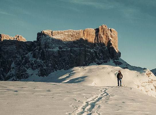 Photographer Nicholas Roemmelt skiing across the top of a mountain towards a rocky outcrop.