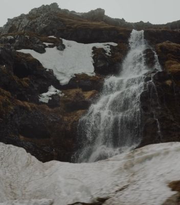 A waterfall crashing down the side of a mountain in Iceland.
