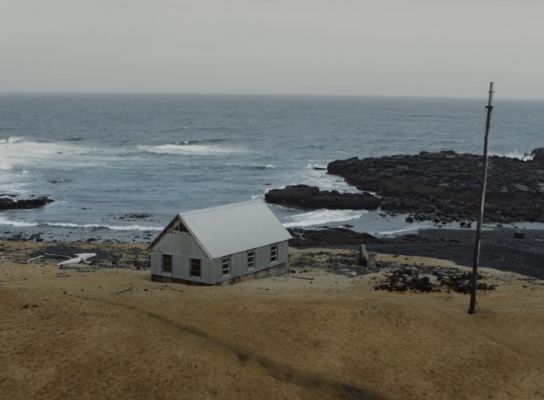아이슬란드 바다가 내려다보이는 절벽 끝에 하얀 오두막이 보이는 풍경