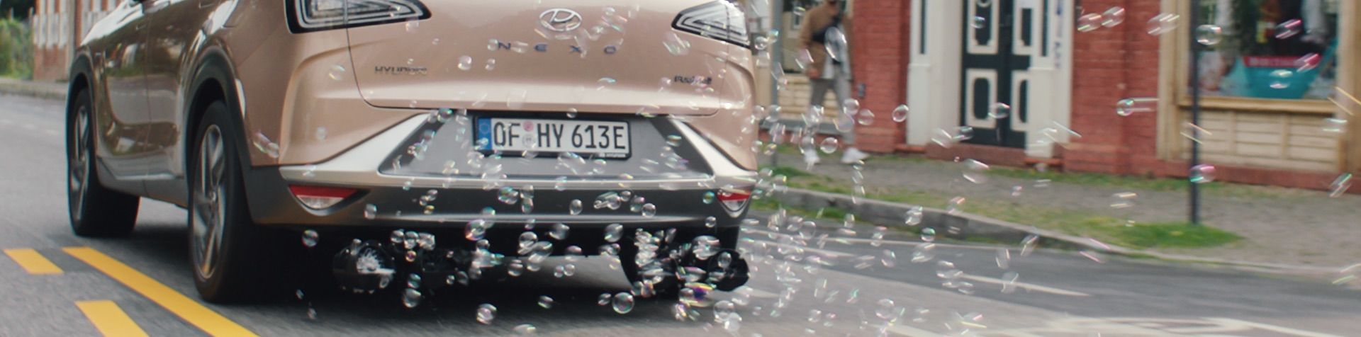 Rear view of a copper Hyundai NEXO with bubbles coming out of the tailpipe. 