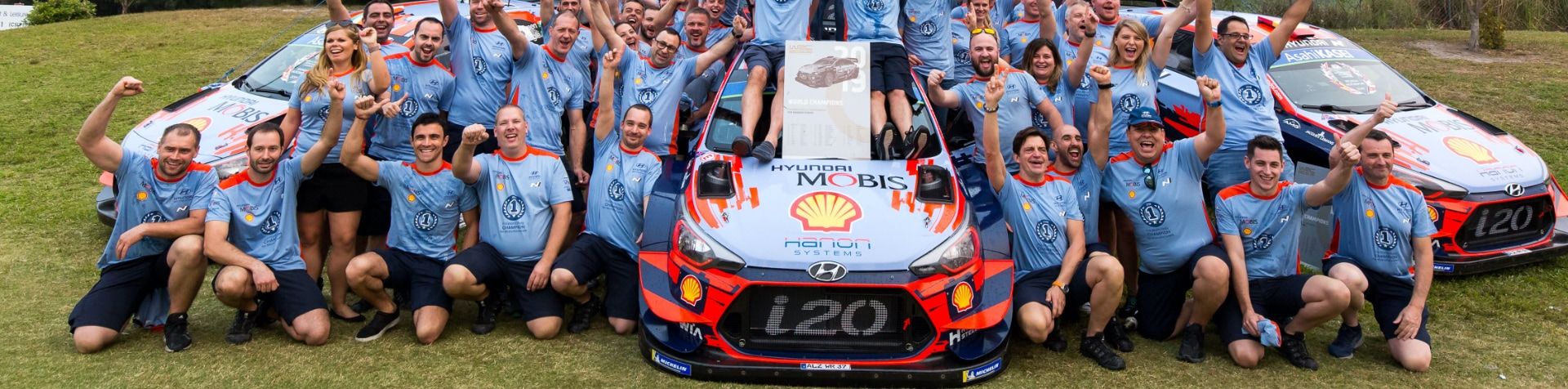 The Hyundai Motorsports team celebrating with 3 i20 WRC cars.