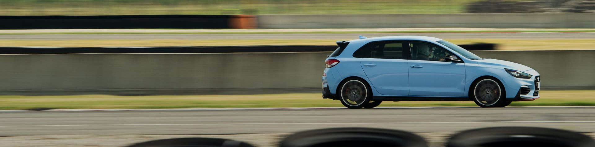 A light blue i30N speeding along a racetrack.