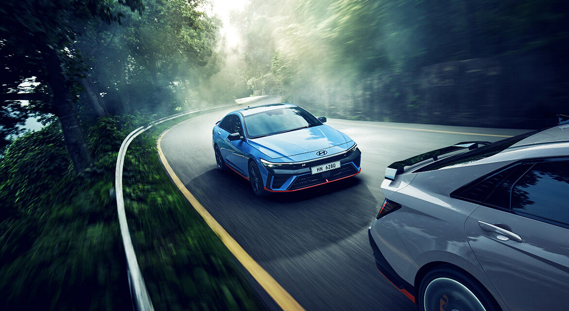 Two of New Elantra N, driving on a winding road, one following the other, three-quarter front view