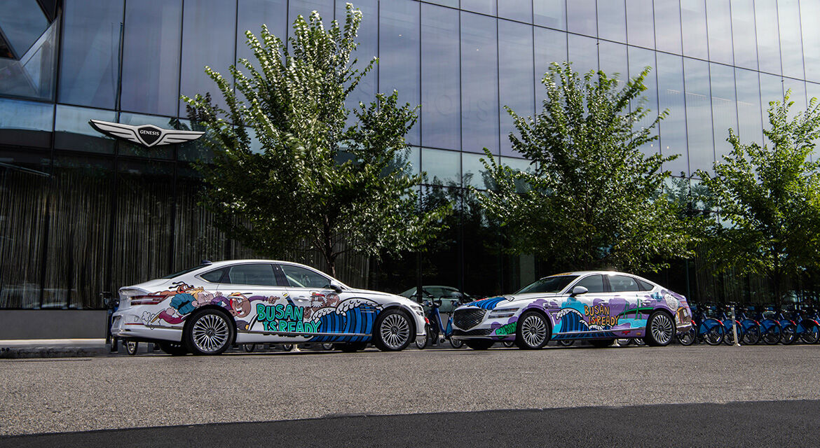 Two Genesis Electrified G80 sedans exhibited at the front of Genesis House New York show graffiti artwork and the slogan to promote Busan's bid to host the 2030 World Expo