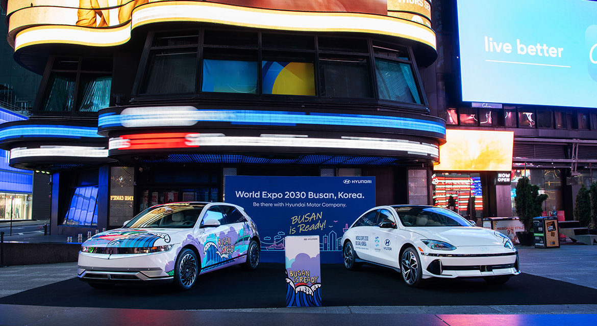 Hyundai IONIQ 5 (left) and IONIQ 6 (right) art cars are exhibited at Times Square, New York, showing graffiti artwork and the slogan to promote Busan's bid to host the 2030 World Expo