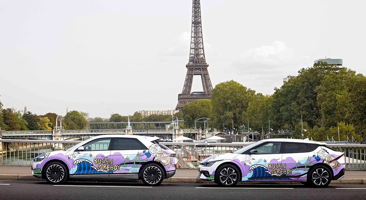 Hyundai Motor's IONIQ 5 (left) and The Kia EV6 (right) art cars are exhibited near the Eiffel Tower, Paris, showing graffiti artwork and the slogan to promote Busan's bid to host the 2030 World Expo