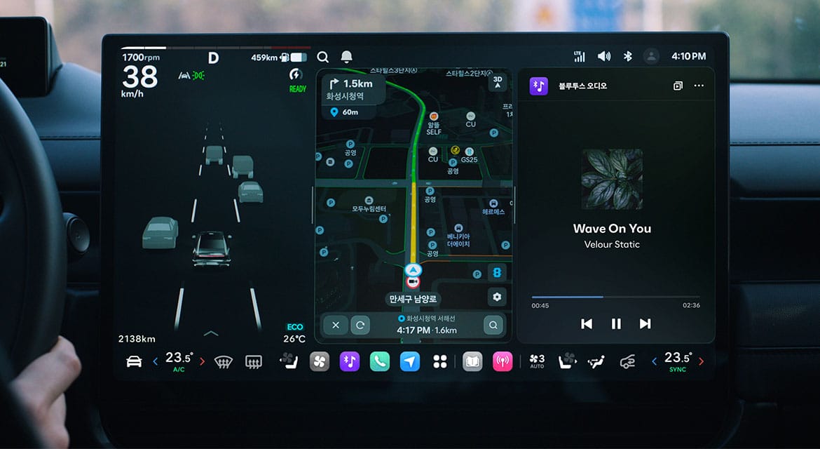 The Large Central Screen of Pleos Connect. The Driving Information Screen on the left visualizes surrounding objects and lane information, while the App Screen on the right runs navigation and Bluetooth audio in Split Screen mode.