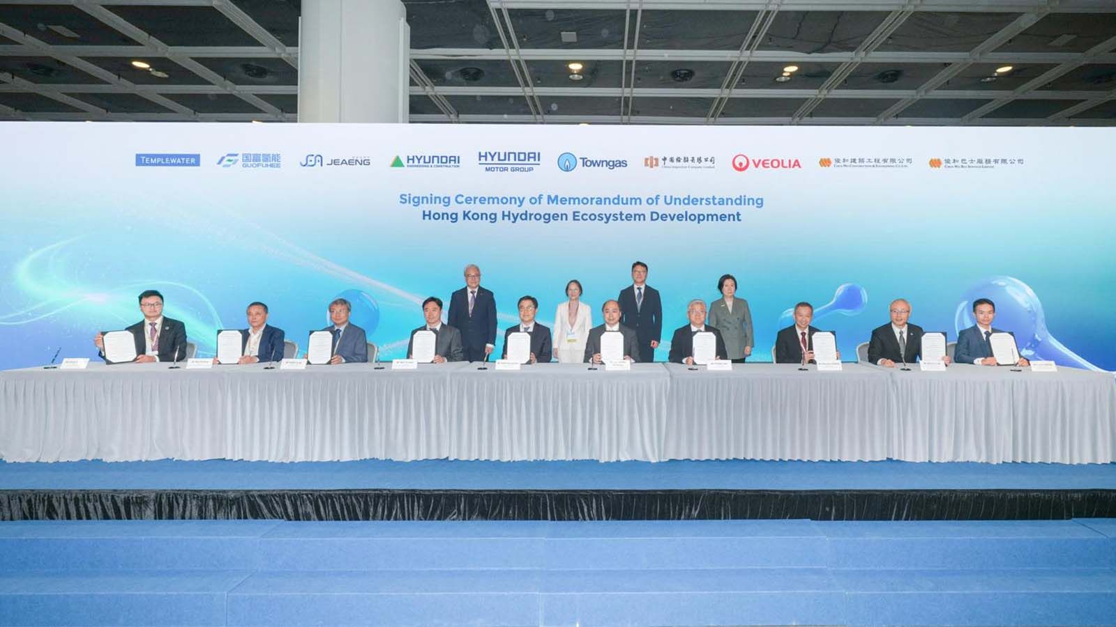 (Back line, Left) Witnesses: Poon Kwok Ying, Director of Electrical and Mechanical Services of the HKSAR; Diane Wong, Acting Secretary for Environment and Ecology of the HKSAR; Jeong Eui Kyung, Deputy Minister of Land, Infrastructure and Transport; Alpha Lau, Director-General of Investment Promotion of Invest Hong Kong  (Front line, Left) Signatories: Alfred Wong, Partner at Templewater Limited; Wu Pinfang, Chairman of Jiangsu Guofu Hydrogen Energy Equipment Co., Ltd.; In Gu Park, Chief Executive Officer of JEA ENG., Co., Ltd.; Yu Taek Seo, Vice President at Hyundai Engineering & Construction Co., Ltd.; Seung Kyu Shin, Executive Vice President and Head of Energy & Hydrogen Policy Sub-Division at Hyundai Motor Group; Cheng Don H.K., Chief Operating Officer – Hong Kong Business at The Hong Kong and China Gas Company Limited; Zhang Jian, Chairman of China Inspection Company., Ltd.; Norman Cheng, Chief Operating Officer of Veolia Hong Kong Holding Ltd.; Ir William Luk, Deputy Chief Executive Officer of Chun Wo Construction and Engineering Company Limited; and Calvin Wong, Chief Executive Officer of Chun Wo Bus Services Limited.